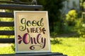 Poster with phrase Good Vibes Only on black wooden bench outdoors