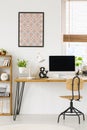 Poster on white wall above wooden desk with lamp and desktop com Royalty Free Stock Photo