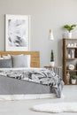 Poster on wooden headboard of bed with grey sheets in bright bed