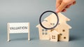 A poster with the word Valuation and a miniature wooden house. Real estate appraisal. Rate the property / home. Appraisal services Royalty Free Stock Photo