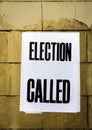 Poster with words Election Called in bold text pasted onto dirty stained yellow brick wall