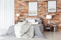 Posters on a bare, red brick wall, above a cozy bed with gray sh Royalty Free Stock Photo
