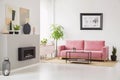 Posters on walls in Scandi sitting room interior with pink velvet couch, fresh plants, fireplace and decor