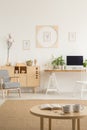 Posters on white wall above desk with desktop computer next to c Royalty Free Stock Photo