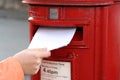 Posting letter to red british postbox