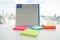 Postit in various colours on office desk for message reminder with december calendar