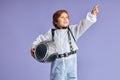 Cheerful caucasian kid cosmonaut isolated over purple background