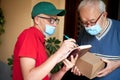 The postman brings the package to the elderly person