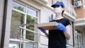 Postman, delivery man in protective mask and medical gloves carry small box parcel. Delivery service under quarantine, pandemic