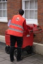 Postman employed by England's Royal Mail with large mail trolley