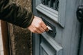 Close-up. The postman puts a letter or newspaper or magazine in the mailbox at the door of a residential building or a