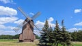 Postmill and pine trees in one line under blue sky