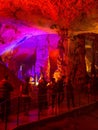 Tourists walking on path among the illuminated stalactites and stalagmites
