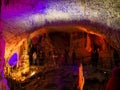 Tourists walking on path among the illuminated stalactites and stalagmites