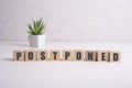 Postponed - words from wooden blocks with letters, postponed concept, top view background