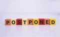 Postponed - words from wooden blocks with letters, postponed concept, top view background