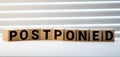 Postponed - words from wooden blocks with letters, postponed concept, top view gray background