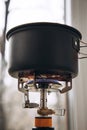 A pot of boiling water on a portable gas burner near the window. The concept of lack of electricity