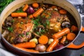 pot of Coq au Vin bubbling on the stove with tender chicken, carrots, and celery in a rich red wine sauce