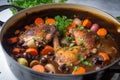 pot of Coq au Vin bubbling on the stove with tender chicken, carrots, and celery in a rich red wine sauce