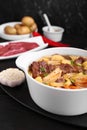 Pot of delicious vegetable soup with meat, noodles and ingredients on black wooden table, closeup Royalty Free Stock Photo