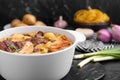 Pot of delicious vegetable soup with meat, noodles and ingredients on black wooden table, closeup. Space for text Royalty Free Stock Photo