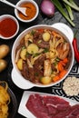 Pot of delicious vegetable soup with meat, noodles and ingredients on black wooden table, flat lay Royalty Free Stock Photo