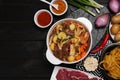 Pot of delicious vegetable soup with meat, noodles and ingredients on black wooden table, flat lay. Space for text Royalty Free Stock Photo