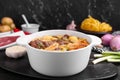 Pot of delicious vegetable soup with meat, noodles and ingredients on black wooden table Royalty Free Stock Photo