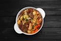 Pot of delicious vegetable soup with meat, noodles and ingredients on black wooden table, top view Royalty Free Stock Photo