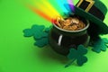 Pot with gold coins, hat and clover leaves on green background. St. Patrick`s Day celebration