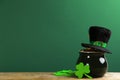 Pot of gold coins, hat and clover leaves on wooden table against green background, space for text. St. Patrick`s Day celebration Royalty Free Stock Photo