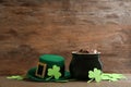 Pot of gold coins, hat and clover leaves on table, space for text. St. Patrick`s Day celebration