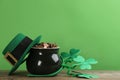 Pot of gold coins, hat and headband with clover leaves on wooden table against green background, space for text. St. Patrick`s Da Royalty Free Stock Photo