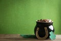 Pot of gold coins, horseshoe and clover leaves on table against green background, space for text. St. Patrick`s Day Royalty Free Stock Photo