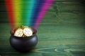 Pot Of Gold on green woden background. Magical Treasure with Rainbow