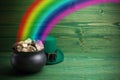 Pot Of Gold on green woden background. Magical Treasure with Rainbow