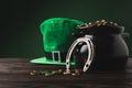 Pot with golden coins, horseshoe and green hat on table Royalty Free Stock Photo