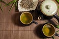 Pot of green tea with cups and plate on a bamboo mat. Royalty Free Stock Photo