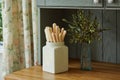 A pot with kitchen utensils and a vase with eucalyptus on a shelf