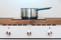 Pot ladle on induction cooker built into wood kitchen worktop view of oven knob relay