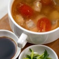 Pot of meat soup or broth with tomatoes, sauce and salad. Close up shot. Top view. Nutritious wholesome food. Delicious