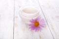 Pot of moisturizing face cream and beautiful flower on a white wooden background. natural organic cosmetic facial. Royalty Free Stock Photo