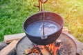 Pot with a piece of meat in the broth hung on the fire. Boiler with soup on a summer day, lifestyle