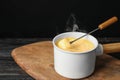 Pot of tasty cheese fondue and fork with bread on wooden table Royalty Free Stock Photo