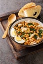 Potaje de Vigilia Spanish chickpea stew with cod and spinach close-up in a bowl on the wooden tray. Vertical