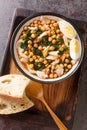 Potaje de Vigilia Spanish chickpea stew with cod and spinach close-up in a bowl on the wooden tray. Vertical top view