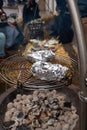 Potato in alumnium foil baked on charcoal barbecue grill outdoor