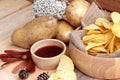 Potato chip and fresh potatoes on wood background Royalty Free Stock Photo