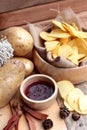 Potato chip and fresh potatoes on wood background Royalty Free Stock Photo